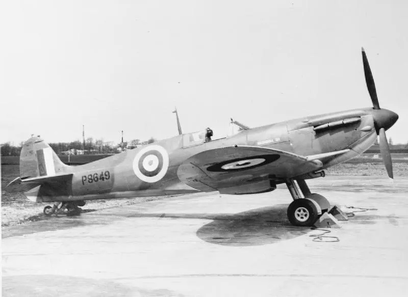 A Spitfire on the ground outside a factory, with workers nearby
