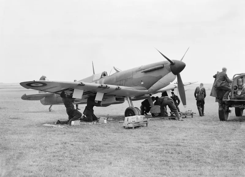 Ground crew re-arming a Spitfire on a grass airfield